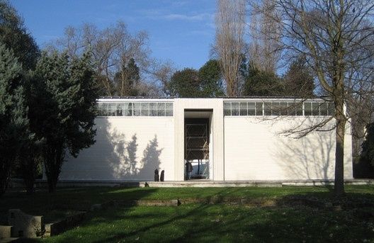White modernist pavilion with geometric facade among trees